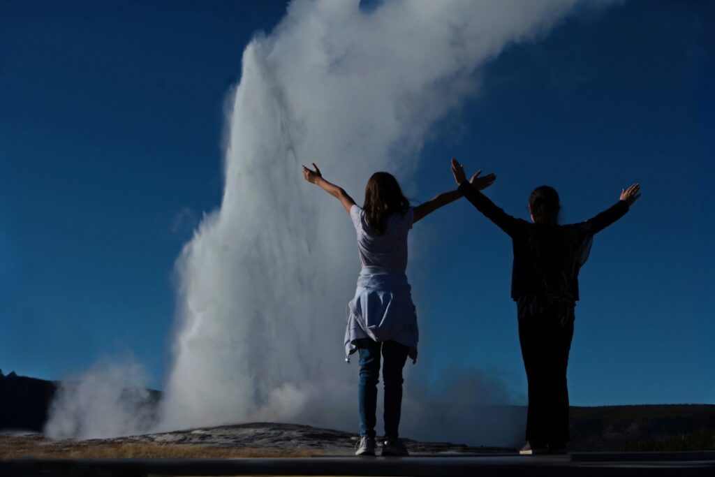 A couple of people that are standing in front of a geyser