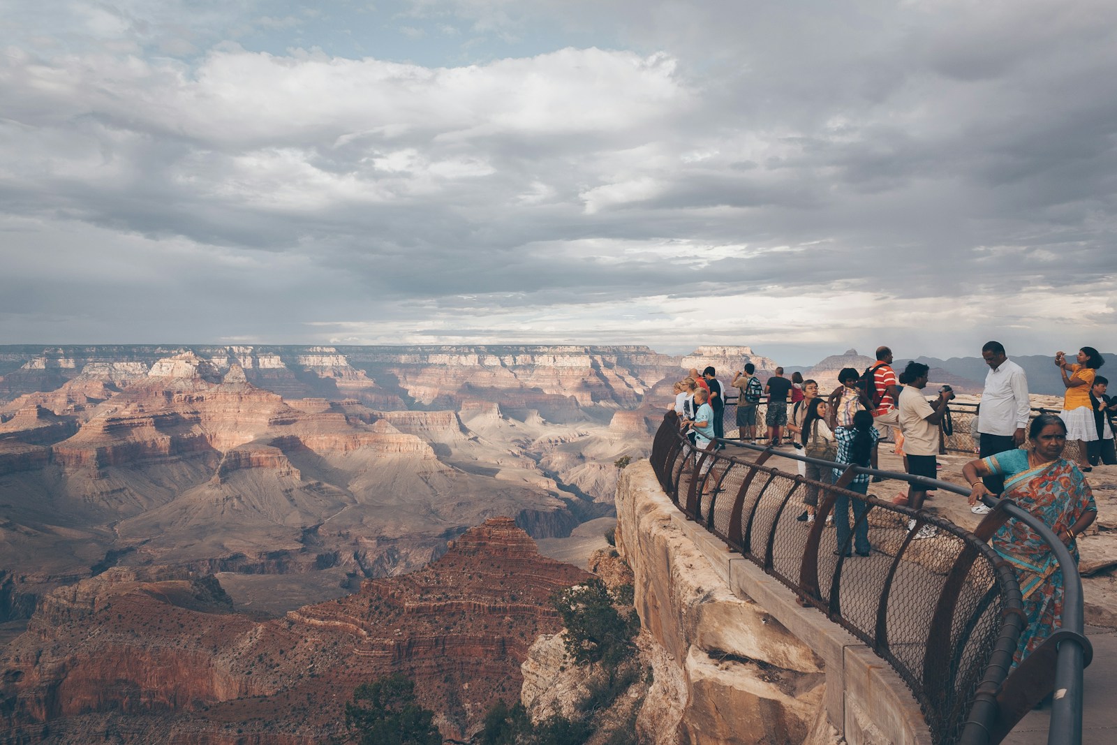 Group of people standing at the top of cliff with railing