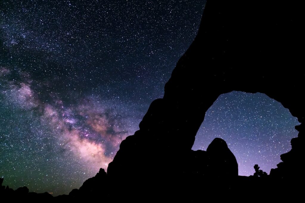 The silhouette of a rock formation against a night sky filled with stars