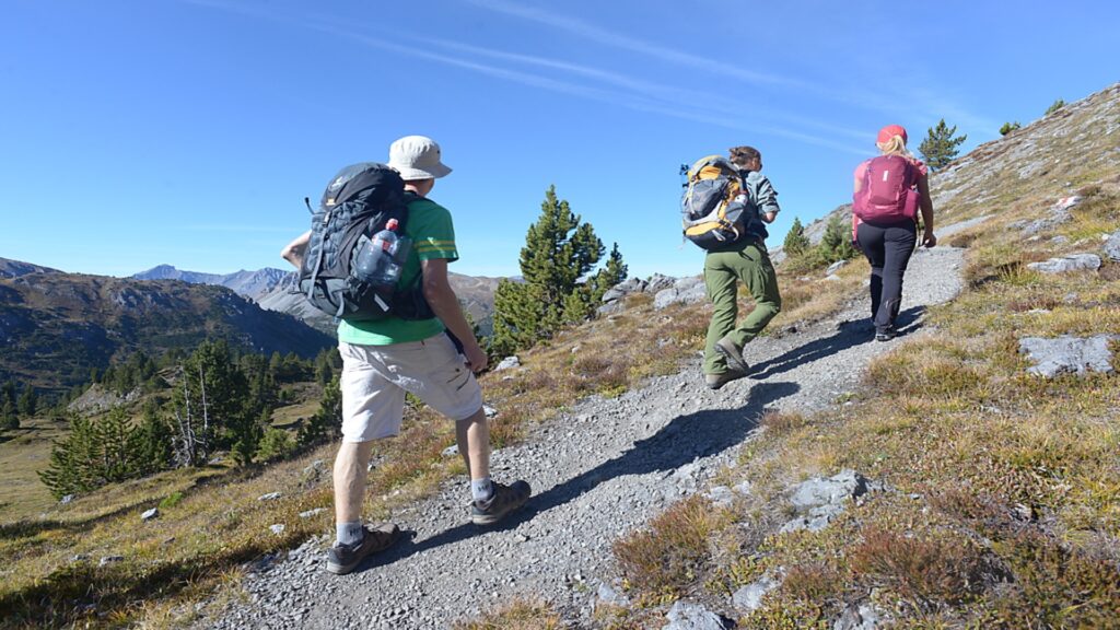 A team of adventurers trekking up a mountain, showcasing determination against a backdrop of towering peaks and blue sky.