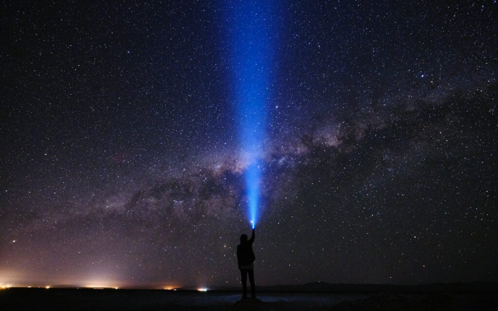 silhouette of man standing on seashore under starry night