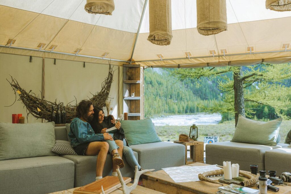 A couple enjoys a relaxing moment inside a luxurious glamping tent with stunning outdoor views.