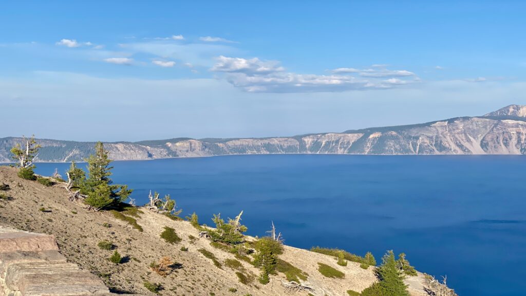 Crater Lake National Park features a breathtaking deep blue lake encircled by steep cliffs and vibrant greenery.