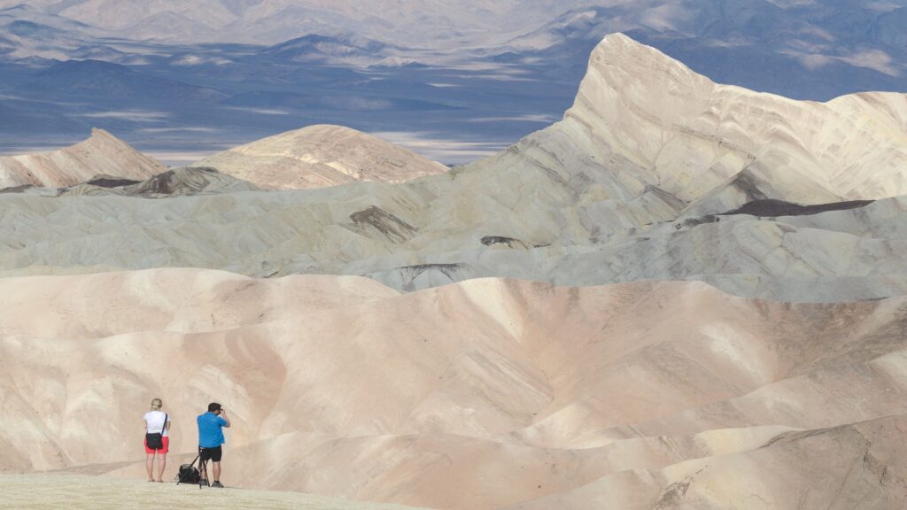 Stunning view of a mountain range, featuring sharp summits and rolling hills, bathed in warm sunlight.