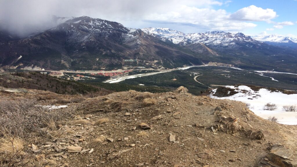Scenic view of a mountain range with a winding river and a road cutting through the lush landscape below.