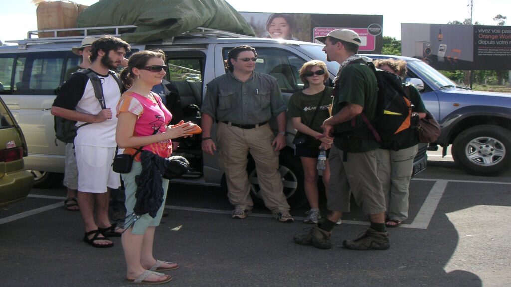 A diverse group of people gathers in a parking lot, representing the Earthwatch Institute's commitment to community engagement.
