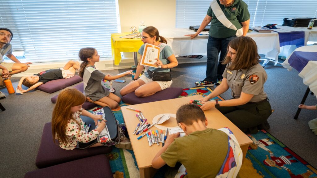 Children of various backgrounds sitting together on the floor, collaborating on a creative project with enthusiasm.