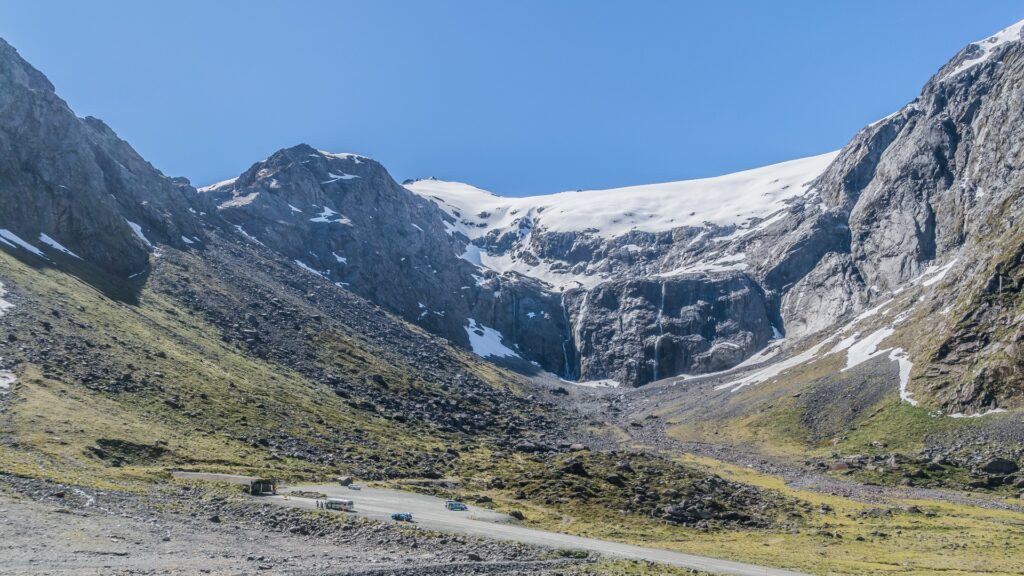 Scenic road ascending a mountain in Fiordland National Park, framed by towering peaks and vibrant wilderness.