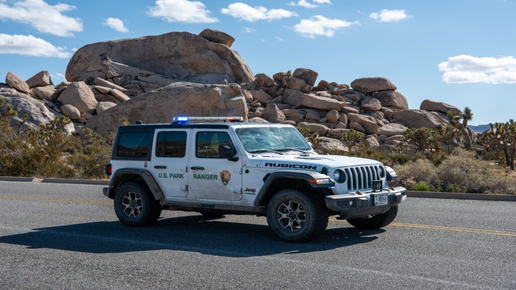 A jeep drives along a rocky road, highlighting the adventurous spirit of the park ranger service in the great outdoors.