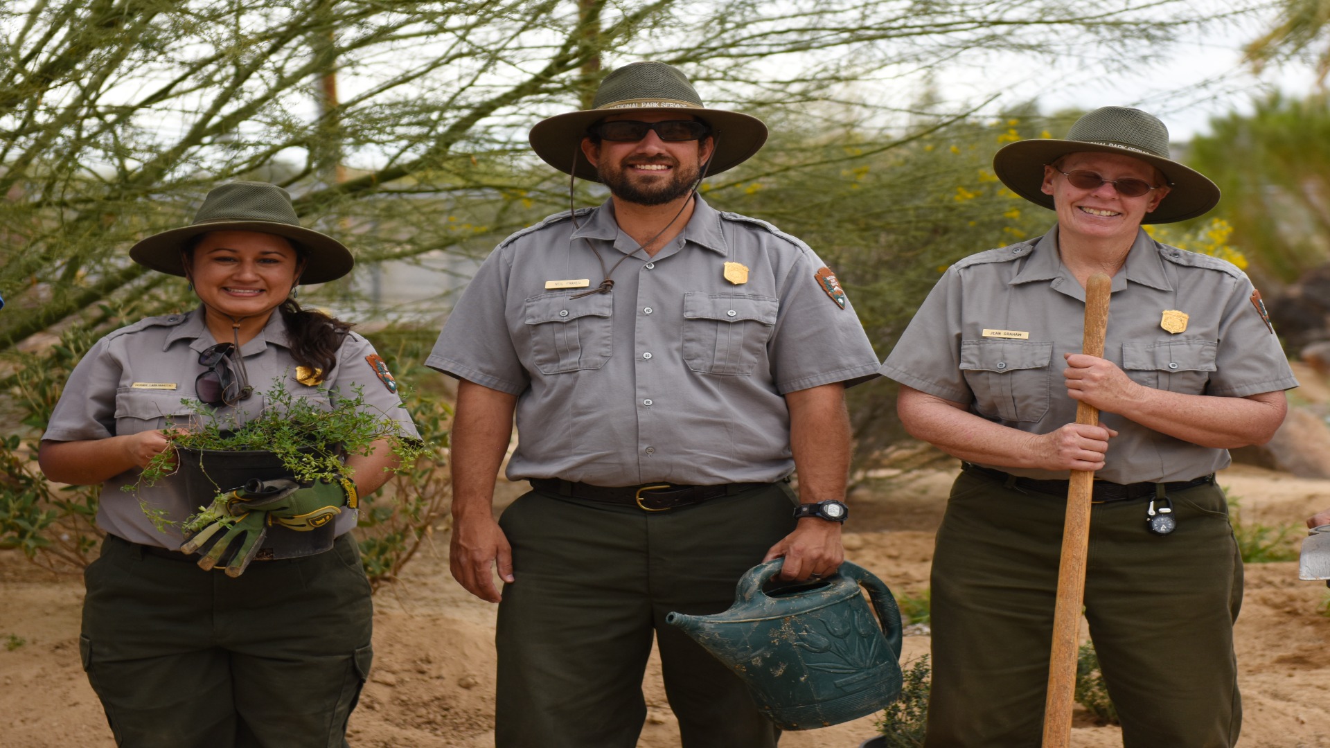 Three park rangers standing together in a vast desert landscape, showcasing their commitment to conservation and nature.