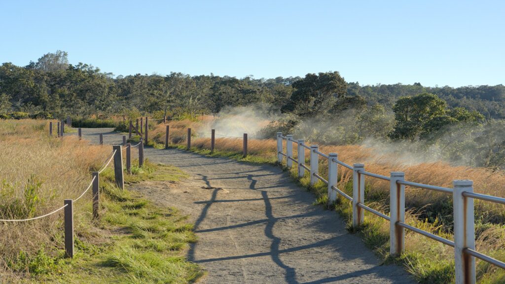 A wooden fence lines the roadside, with lush greenery and volcanic landscapes of Hawaii Volcanoes in the background.