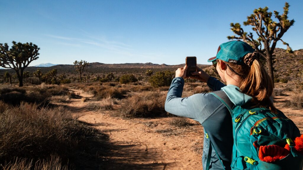 A woman captures a photo against a clear blue sky, showcasing the unique desert landscape.