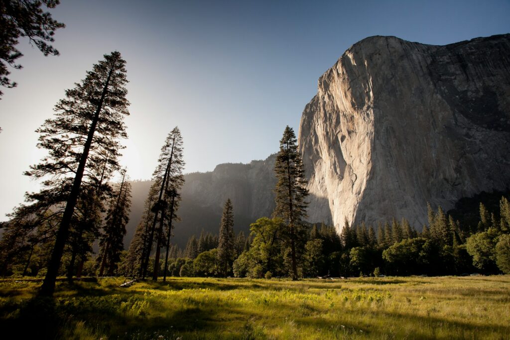 Sunlight illuminates a majestic mountain peak in Yosemite National Park, highlighting its natural beauty and grandeur.