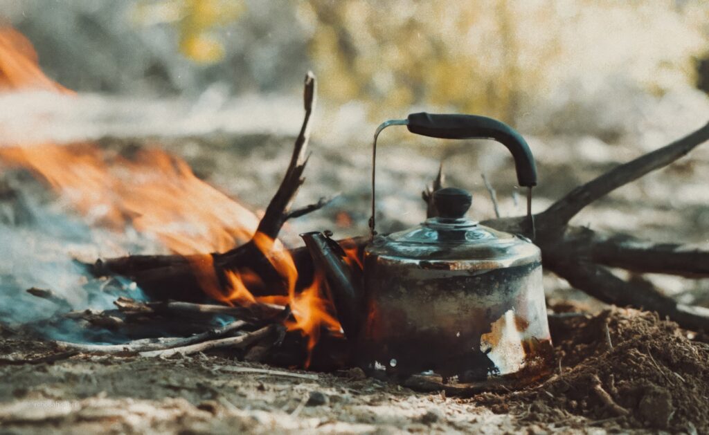 A tea kettle sitting on top of a fire.