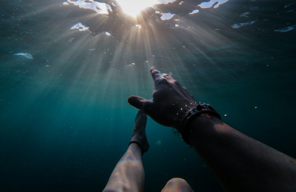 A hand reaches toward the sun, symbolizing hope and connection with nature.