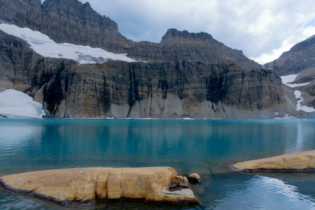 A peaceful lake encircled by dramatic mountains and stones, highlighting the stunning harmony of the wilderness.