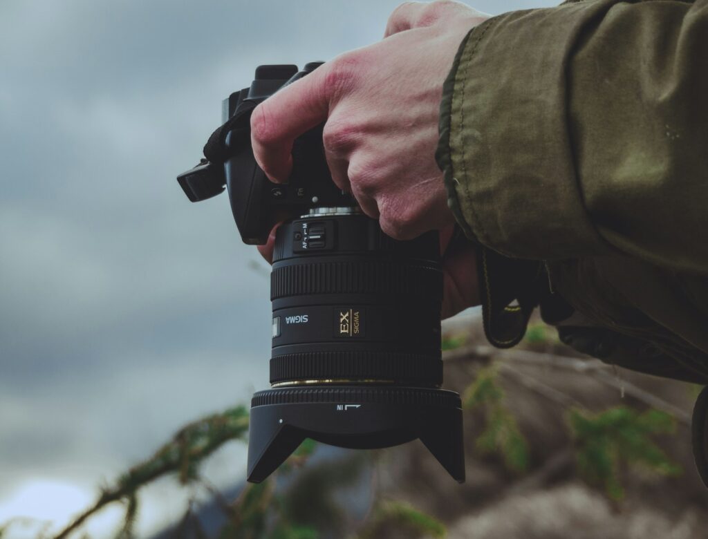 Person holding black DSLR camera.