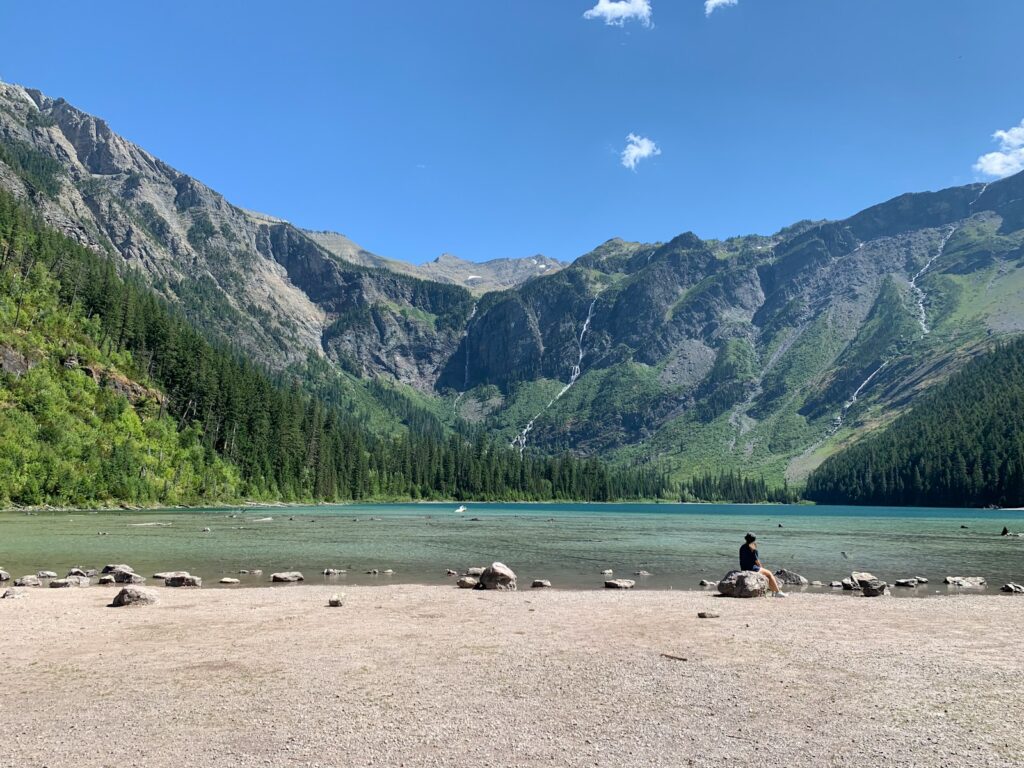 people on lake near green mountains during daytime