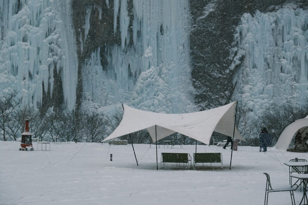 a tent set up in front of a frozen waterfall