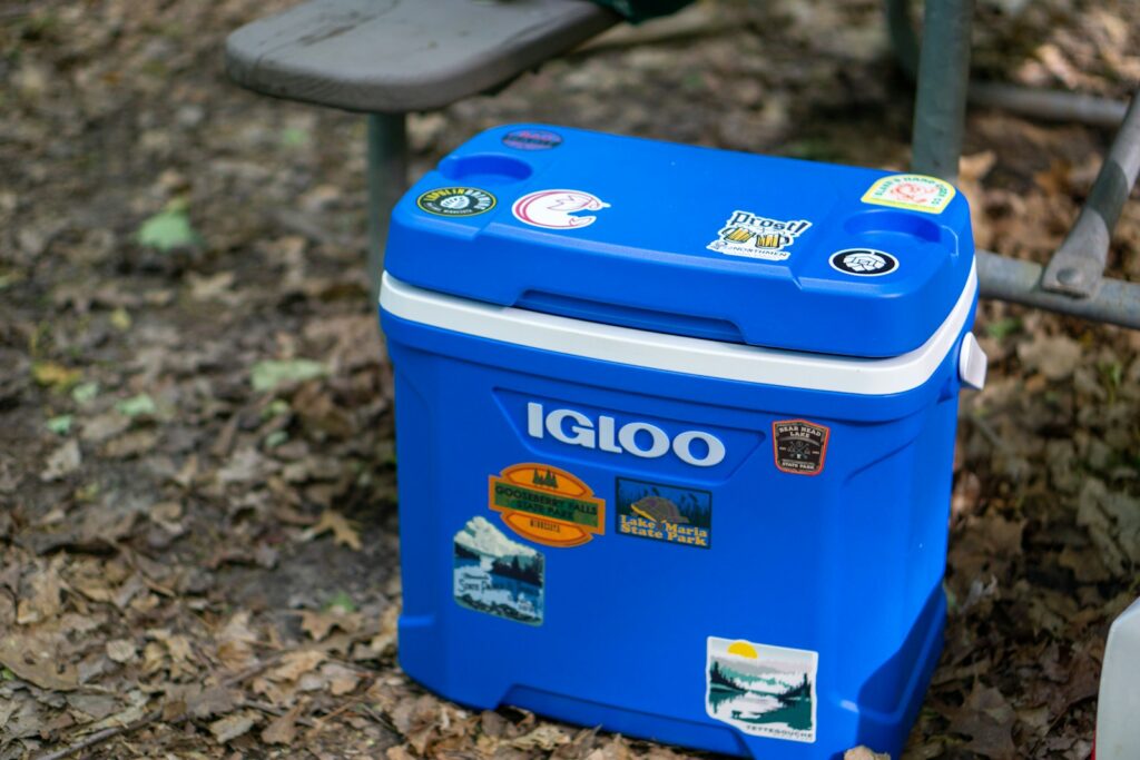A blue cooler sitting on the ground next to a bench
