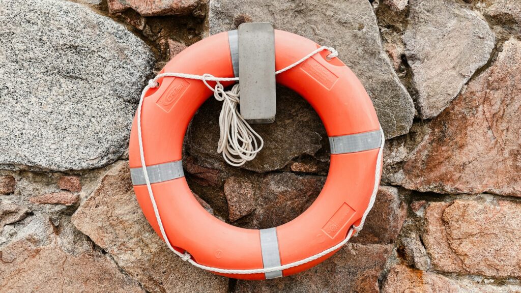 A bright orange life preserver is mounted on a wall, serving as a reminder of safety measures for aquatic activities.