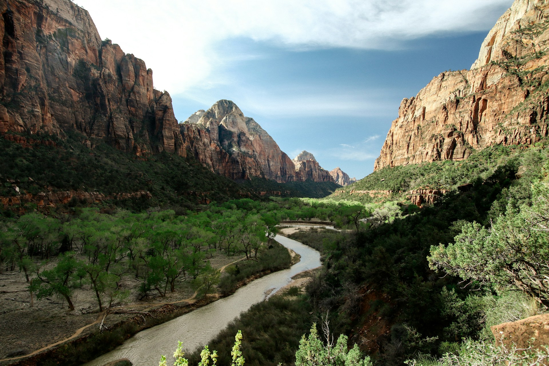 A serene view of the Virgin River flowing through Zion National Park's majestic canyon, surrounded by towering cliffs.