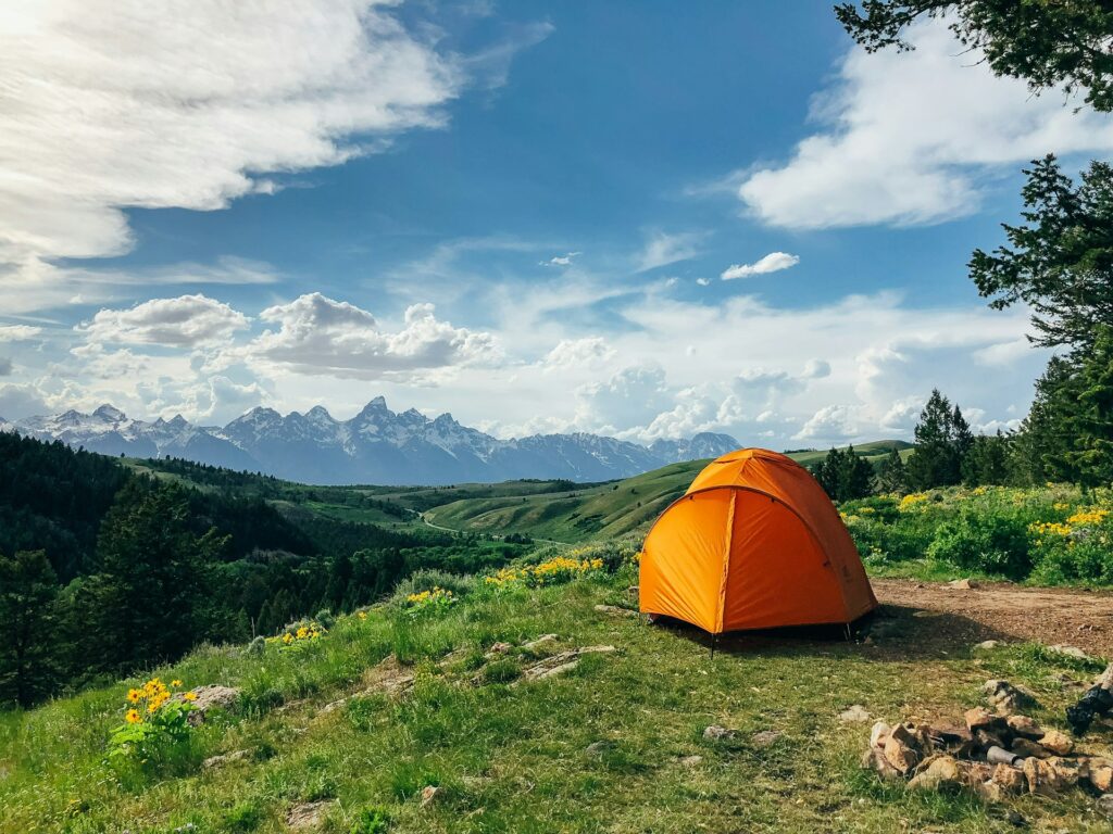 A vibrant tent set against a stunning mountain backdrop, inviting adventure in the great outdoors.