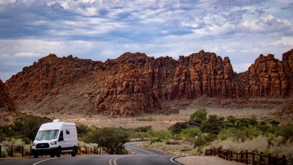 a van driving on a road in front of a rocky mountain