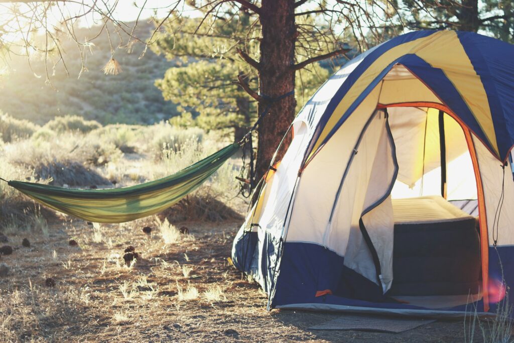 A cozy tent set up in a forest, with a hammock nearby, inviting for a relaxing outdoor adventure.