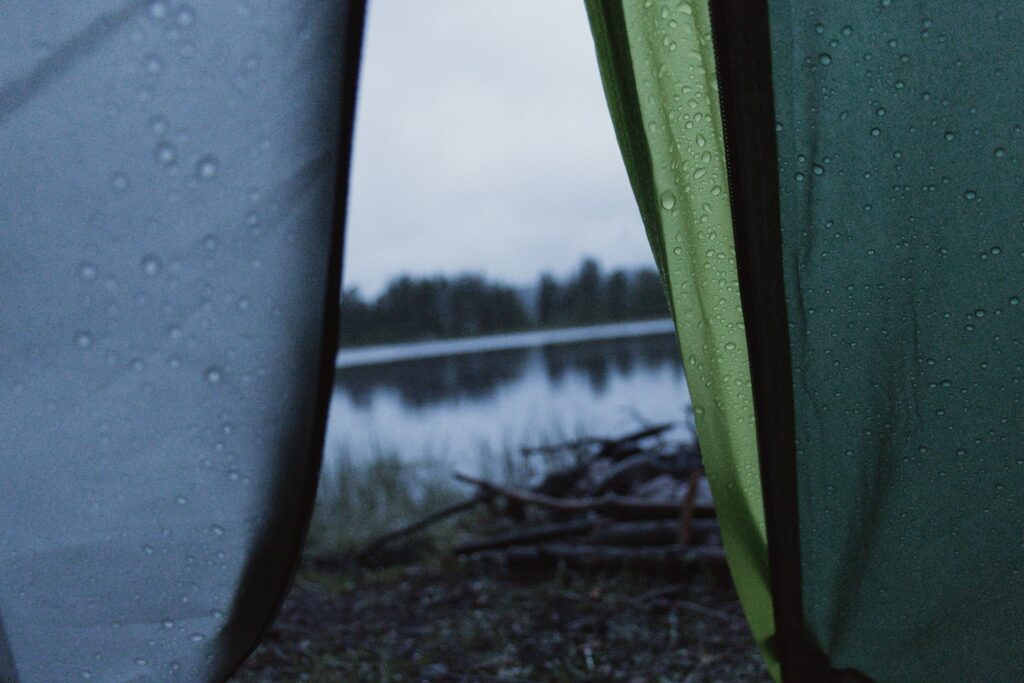 A calming lake vista visible through a tent, showcasing the harmony of camping and nature's tranquility.