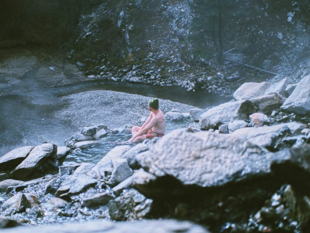 man sitting on rock in river