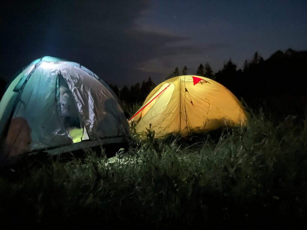 Two glowing tents illuminate the night, creating a cozy and inviting atmosphere under the starry sky.