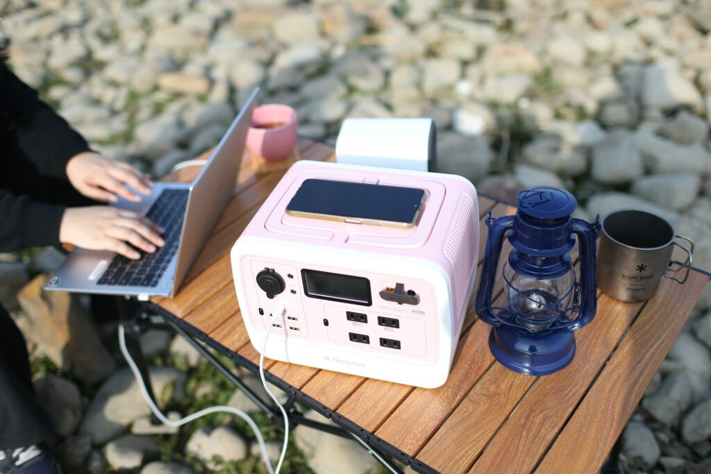 A person at a table using a laptop next to a solar-powered device, showcasing a blend of technology and sustainability.