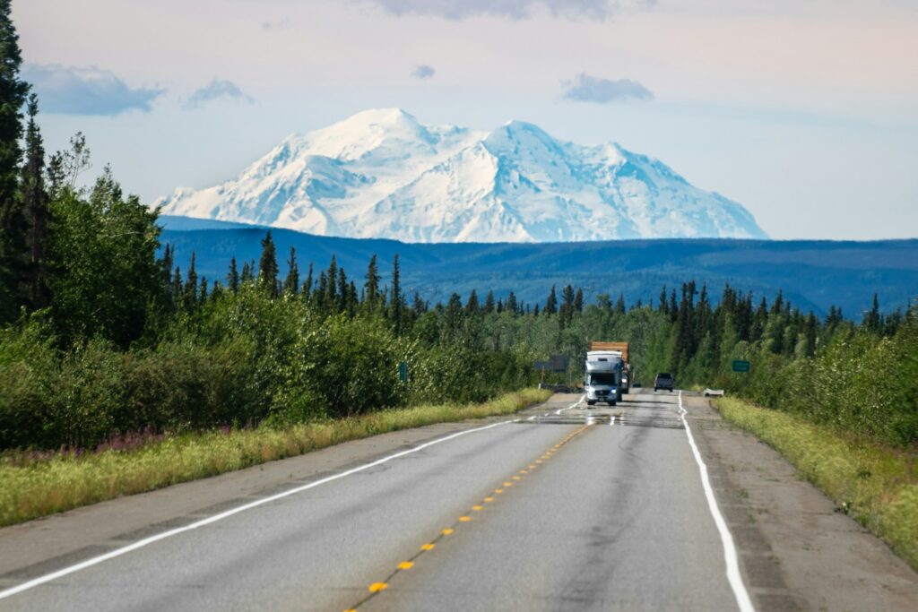 A truck driving down a road with a mountain in the background
