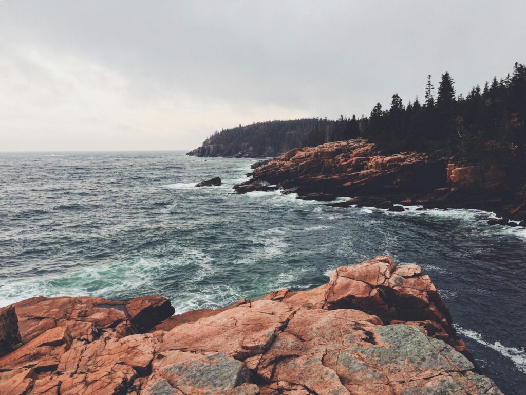 brown rocky mountain beside body of water during daytime