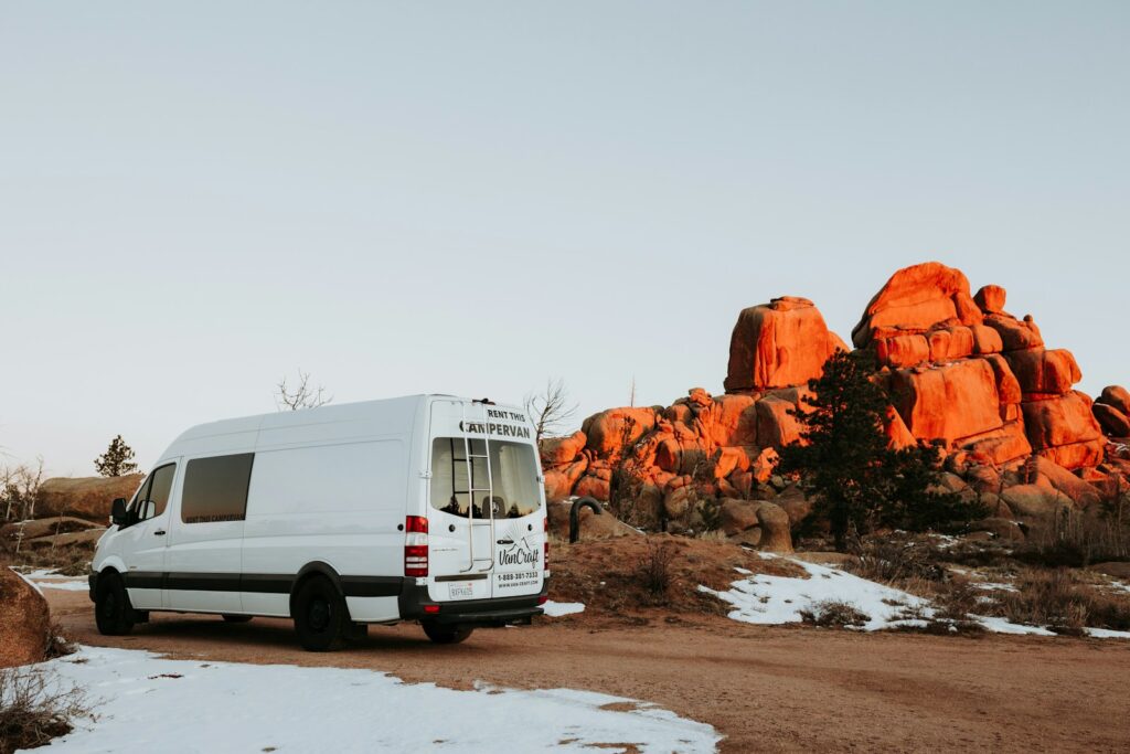 a white van parked in front of a large rock formation