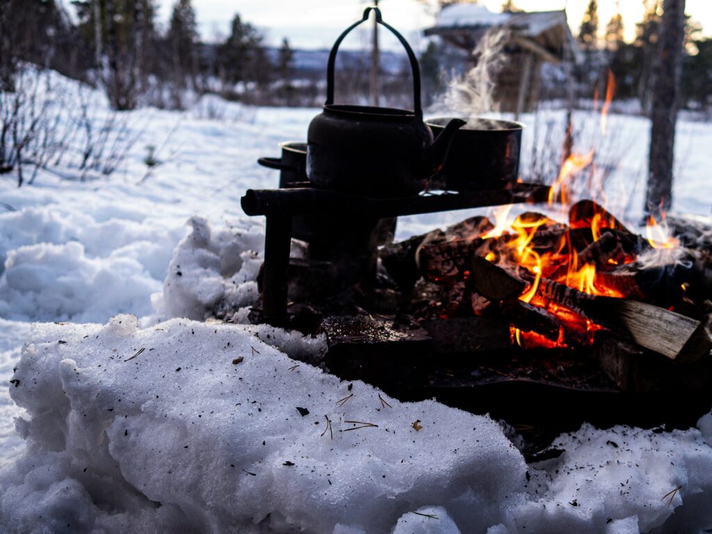 A cozy fire pit with a kettle resting on top, ready for brewing a warm beverage outdoors.