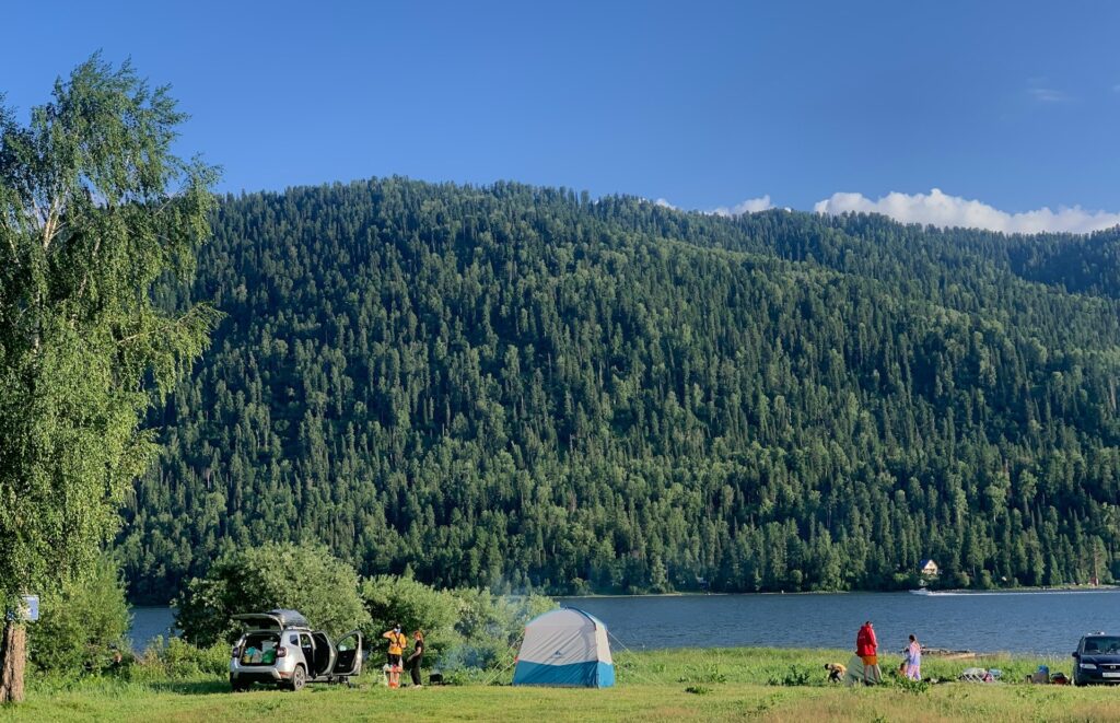 A picturesque lake view showcasing a tent and a car, perfect for a peaceful getaway in nature.