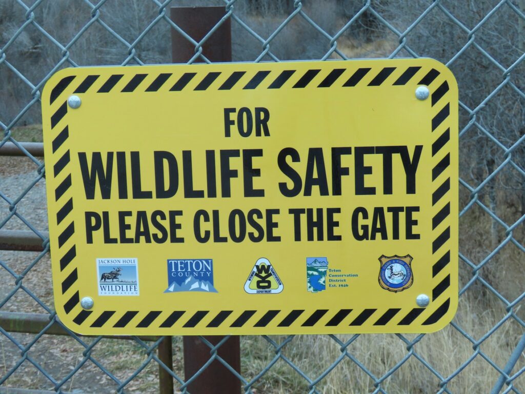 A warning sign urging people to close the gate to ensure the safety of wildlife in the surrounding area.