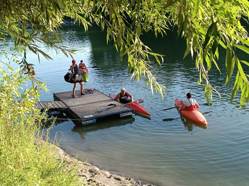 A lively scene on a dock with people chatting and colorful kayaks lined up, ready for a day of adventure on the water.