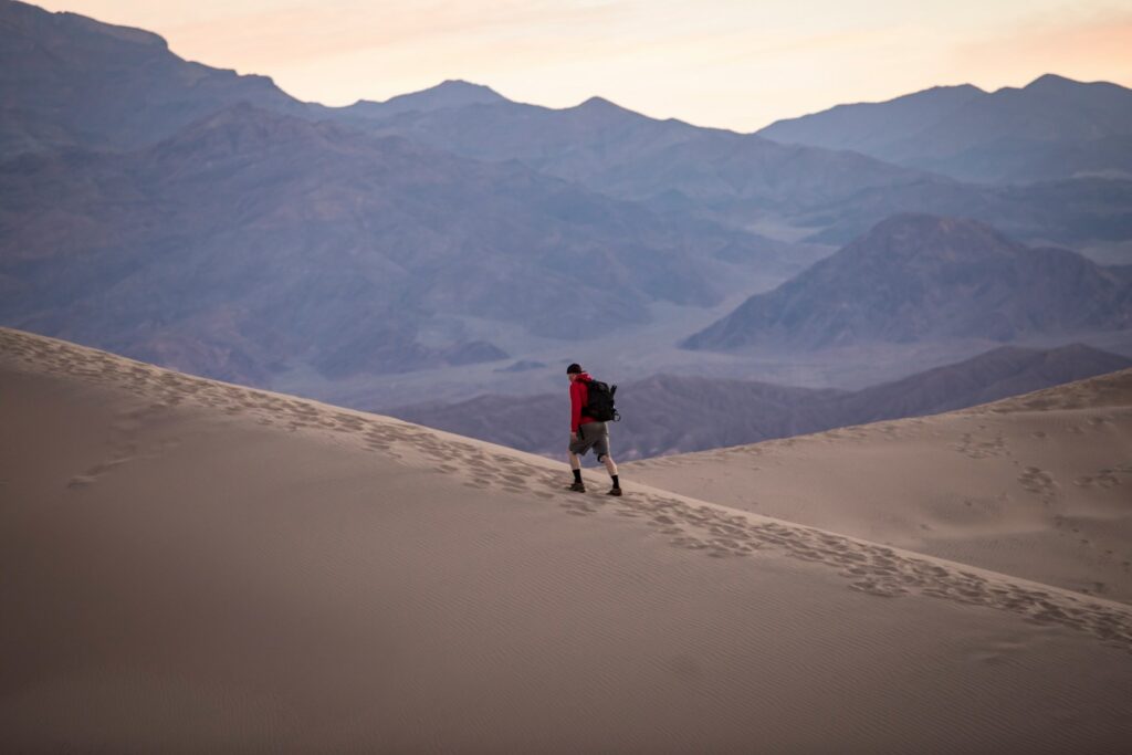 person in red hoodie walking on desert