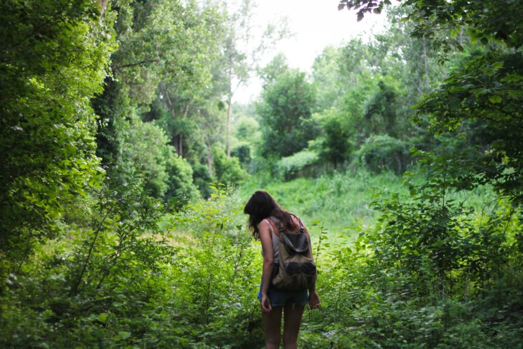 Woman with backpack near green trees