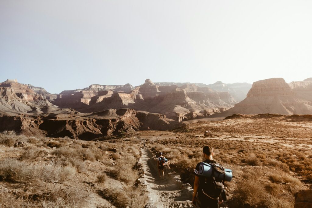 man walking on empty place surrounded by brown rock formation