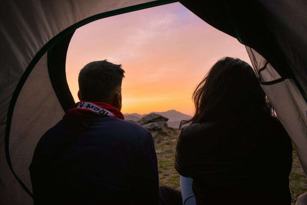 Man and woman sitting inside a tent during daytime.