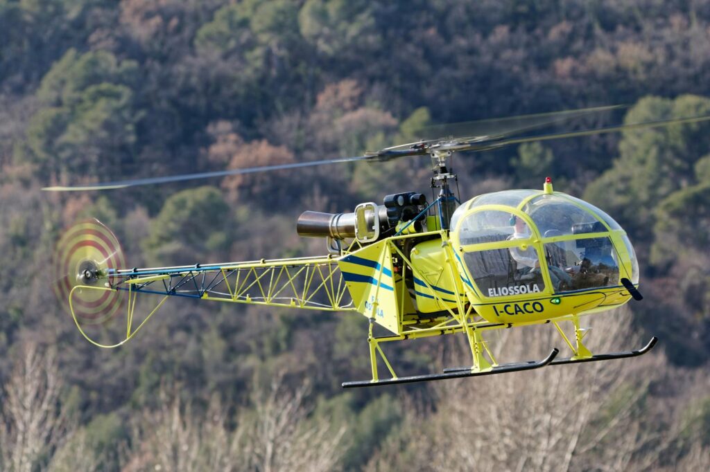 A vintage helicopter flying outdoors on a sunny day, showcasing its classic design and vibrant colors.