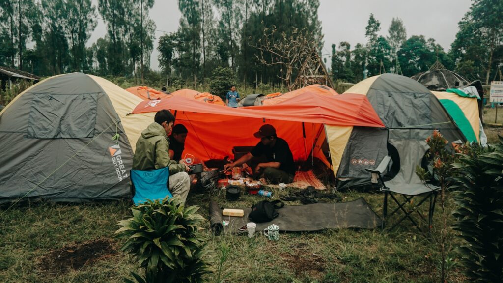 A group of people sitting outside of tents.