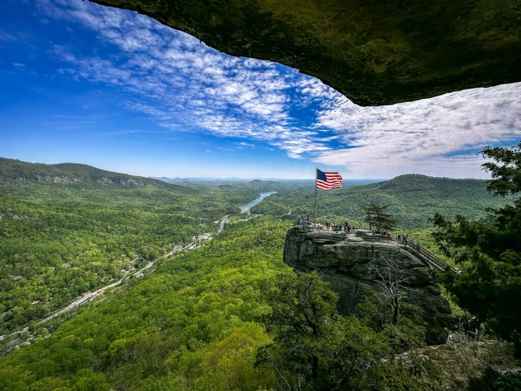 an american flag on top of a mountain overlooking a valley