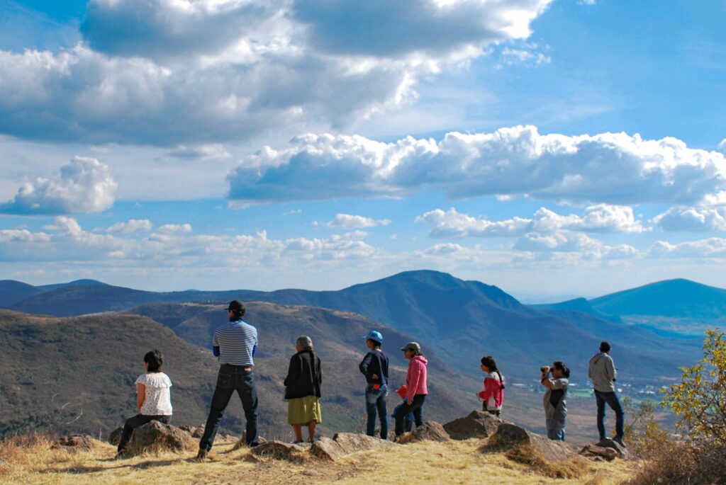 Group of people standing on brown rock mountain during daytime.