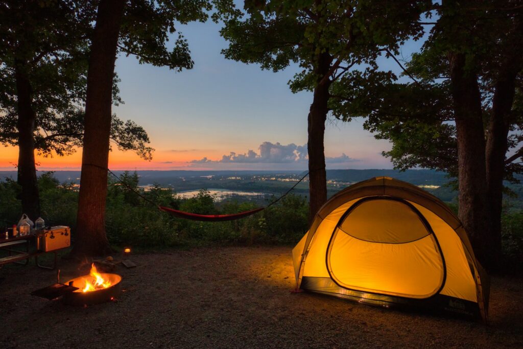 A tent set up in the woods at sunset.