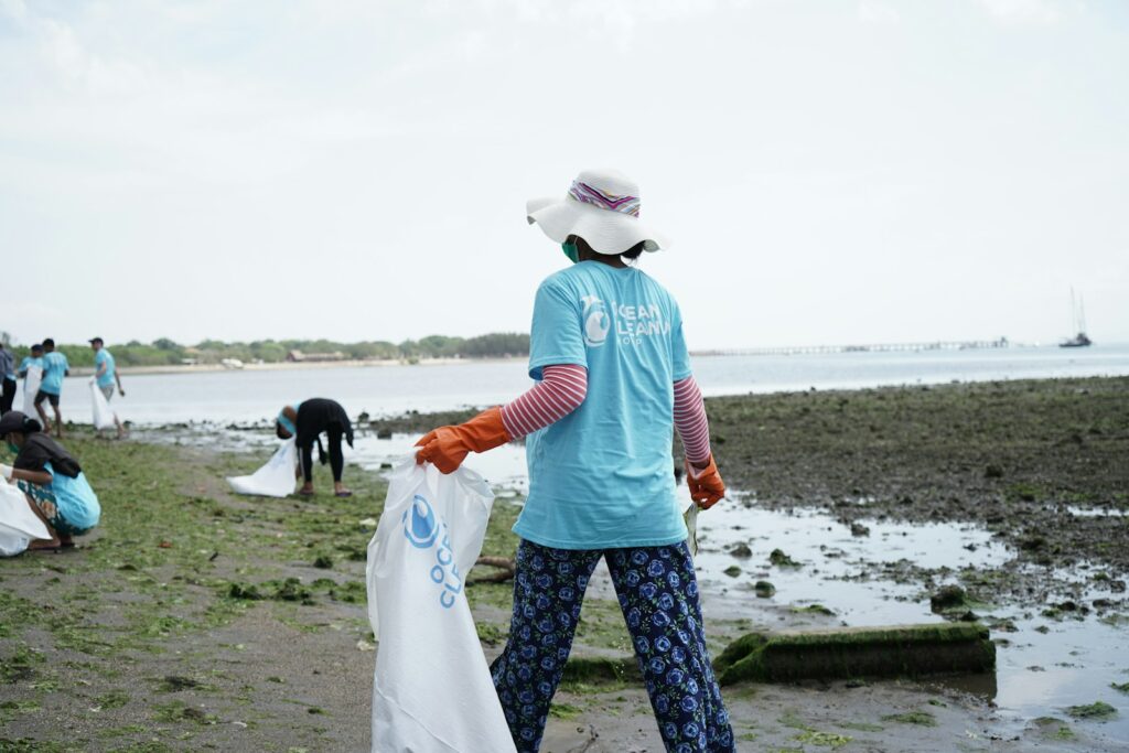 woman in white sun hat holding black short coat dog on beach during daytime